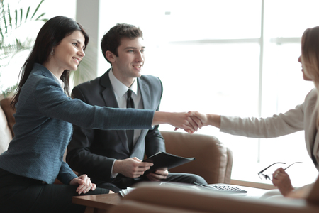 two business women hold each other by the hands,sitting at the Deskの写真素材