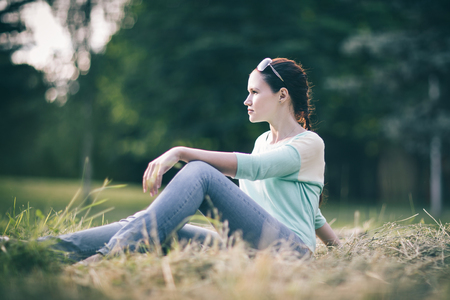 young woman sitting on the grass in the Park.の写真素材