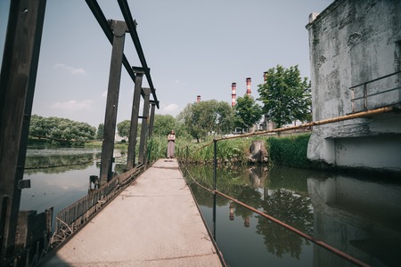young hippie woman standing on wooden bridge on summer dayの写真素材