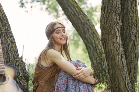 beautiful hippie girl sitting near trees in forestの写真素材