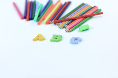 colored pencils and letters of the alphabet on a white background .photo with copy space