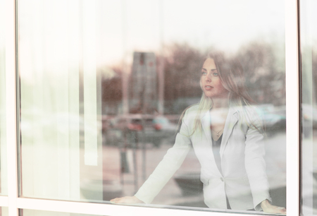 successful business woman looks out the window of his officeの写真素材