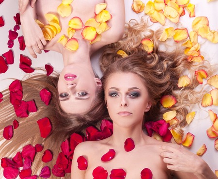 two beautiful young women relaxing lying among rose petals.の写真素材