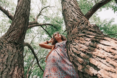 young hippie woman standing near an old tree.の写真素材