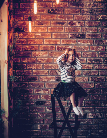 portrait of a little girl on a brick wall background.の写真素材