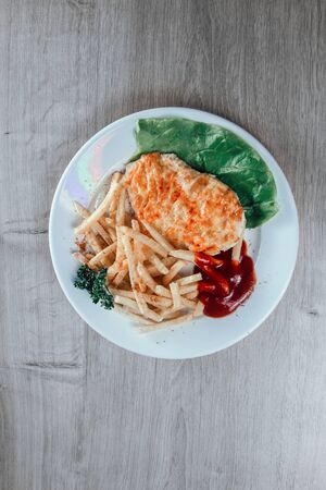 chicken chop and fried potatoes on white plateの写真素材
