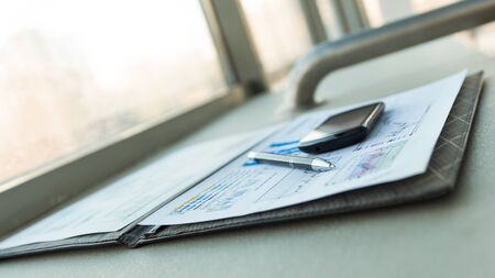 mobile phone and financial documents on the desktop.