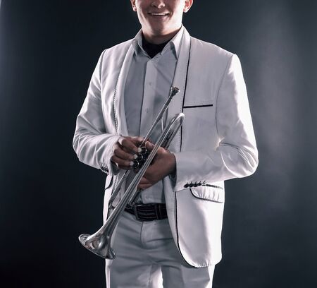 Young man in a white suit with a trumpet.isolated on black