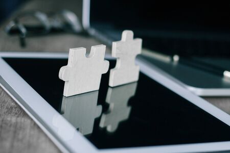Piece of the puzzle on the screen of the tablet on the desktop