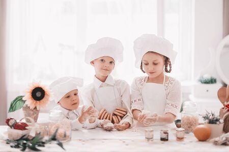 Three happy baby cooks standing near the kitchen tableの写真素材