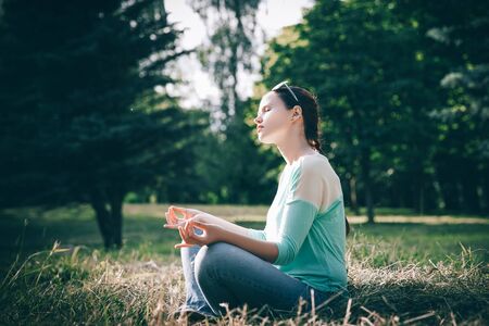 side view.beautiful woman meditating in Lotus position outdoorsの写真素材