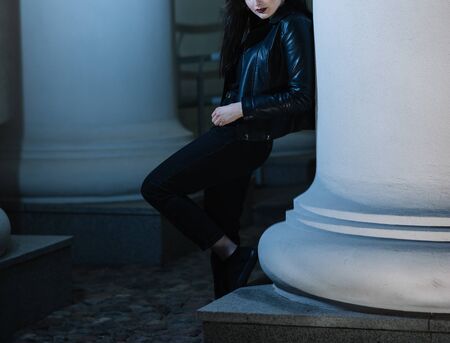 stylish young woman standing near a pillar of a city buildingの写真素材