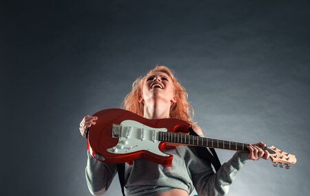 Attractive girl emotionally playing the electric guitar.の写真素材