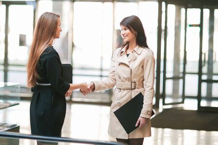 two businesswomen shaking hands in the office lobby.の写真素材