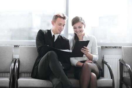 employees discussing business document sitting in the lobby of the officeの写真素材