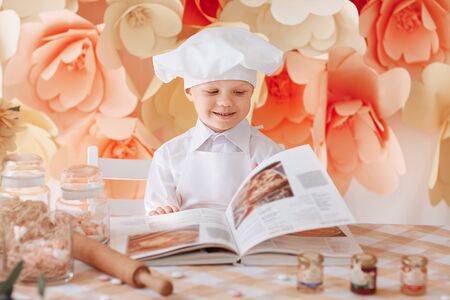 happy boy chef chooses a cooking recipeの写真素材