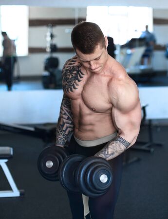 Muscular man doing exercises with dumbbells on the bicepsの写真素材