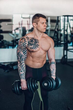 portrait of handsome male bodybuilder with dumbbellsの写真素材
