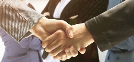 close up. confident businessmen shaking hands on background of business partners.