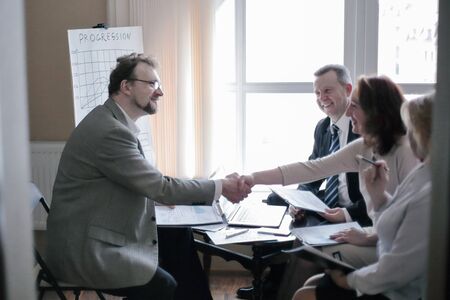 handshake business women and business men near the desktopの写真素材