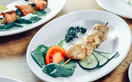 kebab and fresh vegetables on a white plate on the table in a kebab shopの写真素材