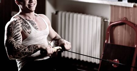 sporty handsome man doing exercises on the home trainer.
