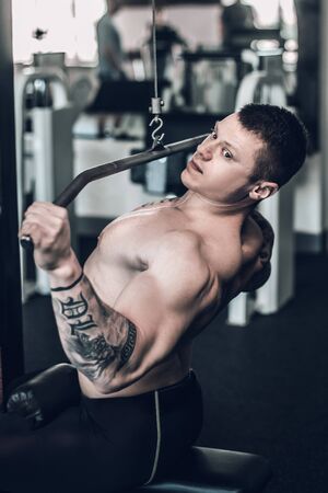 Male bodybuilder uses the simulator to strengthen the muscles of the chest