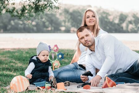 Happy family sitting on the grass in the Park
