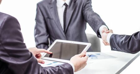 businessman with digital tablet on background of business partners handshakingの写真素材