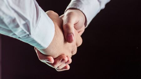 concept of a reliable partnership: a close-up of handshake of business partners on black background.の写真素材