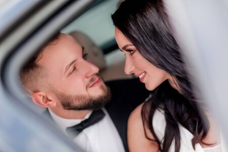 close up. the bride and groom look at each other sitting in the carの写真素材