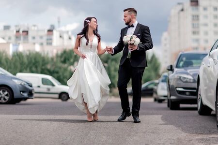 happy bride and groom walking down the street in the big city