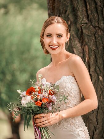 beautiful bride standing near a tree in the city Parkの写真素材