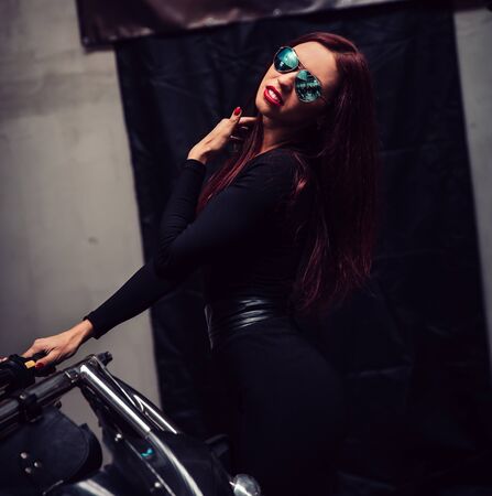 fashionable young woman standing near black trikeの写真素材