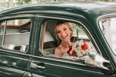 happy bride looking through the window of the caの写真素材