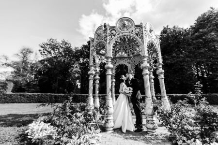 Happy bride and groom standing in arched gazeboの写真素材