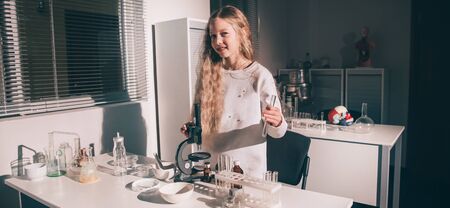 Schoolgirl with chemical flask standing near the table in the school officeの写真素材