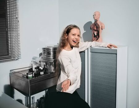 cheerful schoolgirl girl standing in the office of the school nurseの写真素材