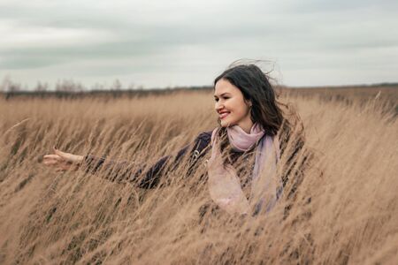 pretty young woman walking on a wheat fieldの写真素材