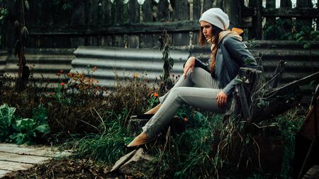 brooding young woman sitting in the village yard.の写真素材