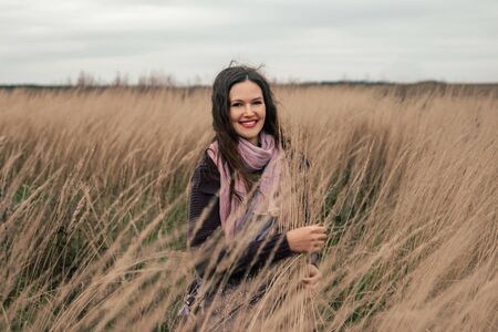 beautiful young woman standing among ripe ears of wheatの写真素材