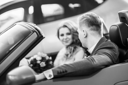 happy bride and groom sitting in a luxury car. black and white photoの写真素材