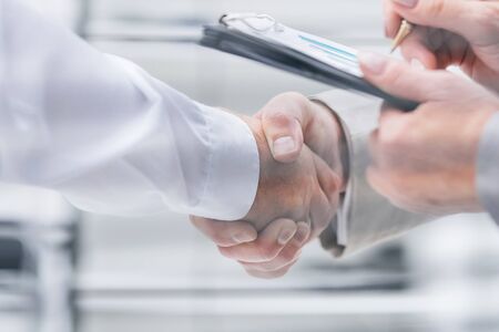 through the blinds. business people completing a transaction in the officeの写真素材