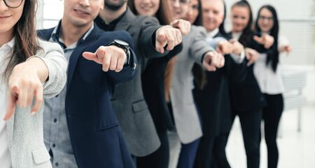 Large group of young business people are pointing at you