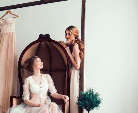 bride with her friends trying on the wedding dress.の写真素材