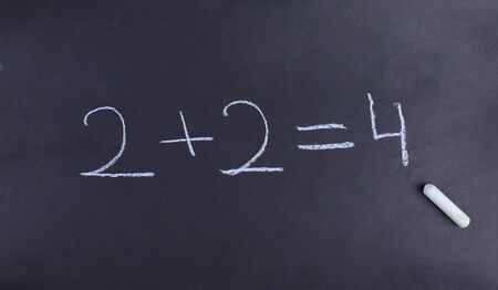 A young student has solved a basic math equation on a chalkboard.