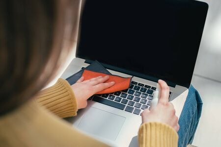 close up. a young woman uses antiseptic to clean her laptopの写真素材