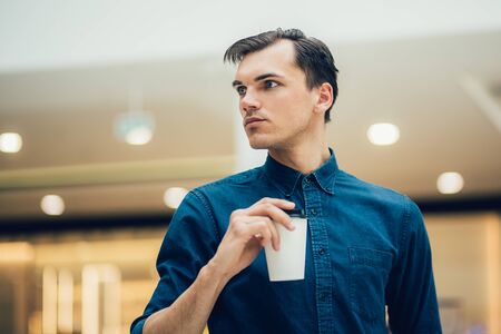 attractive young man with a coffee to take away
