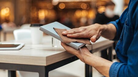 man in a protective mask processing personal belongings with antisepticの写真素材