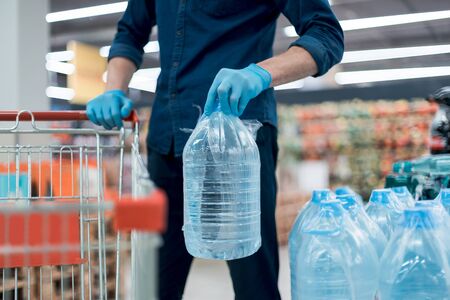 man in protective gloves with a bottle of drinking water.の写真素材